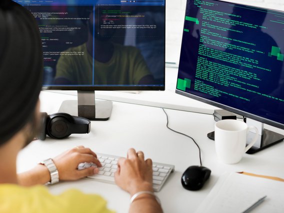 Person an zwei Computer-Bildschirmen Person an zwei Computer-Bildschirmen