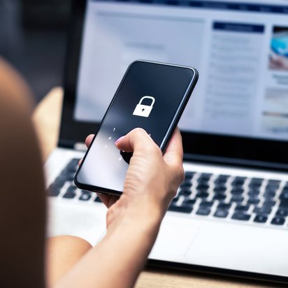 Eine Frau gibt an ihrem Smartphone eine PIN ein. PIN-Eingabe am Handy