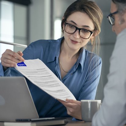 Frau mit Blatt Papier Eine Frau zeigt einem Mann etwas auf einem Dokument, auf dem Textpassagen markiert sind.