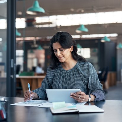 Frau mit Tablet und Papier Eine Frau arbeitet an einem Tisch mit einem Tablet und Papier.