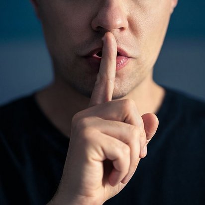 Zeigefinger als Zeichen für Ruhe Eine Person signalisiert mit dem Zeigfinger am Mund Ruhe.